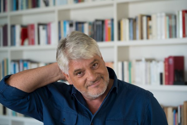 Der Autor Raoul Schrott vor einer Bücherwand.