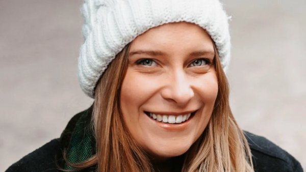 Ivy Leagh lächelt mit weißer Strickmütze