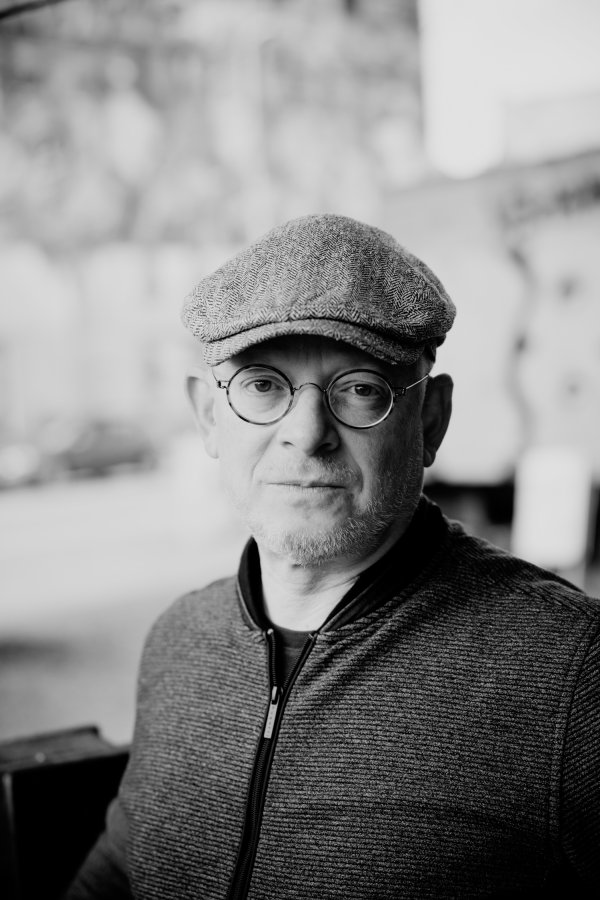 Portrait des Autors Timur Vermes in schwarz-weiß. Er trägt eine Kappe und eine runde Brille.