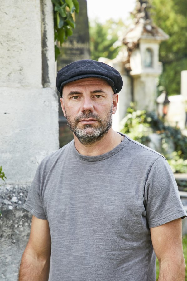 Portrait des Autors Daniel Wisser. Er steht im Freien und trägt eine schwarze Kappe.