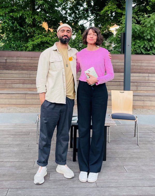 Portrait von Louise Brown (rechts) und Cihan Morsünbül (links). Frau Brown trägt ein pinkes Oberteil und eine dunkle Hose. Herr Morsünbül trägt eine helle Jacke und Kappe.