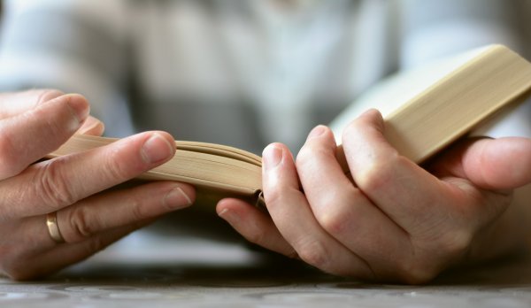 Zwei Hände halten ein aufgeschlagenes Buch
