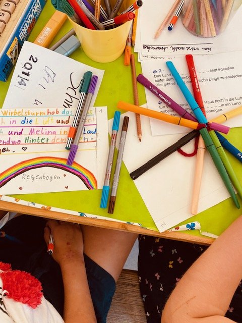 Papier und bunte Stifte auf einem Tisch.