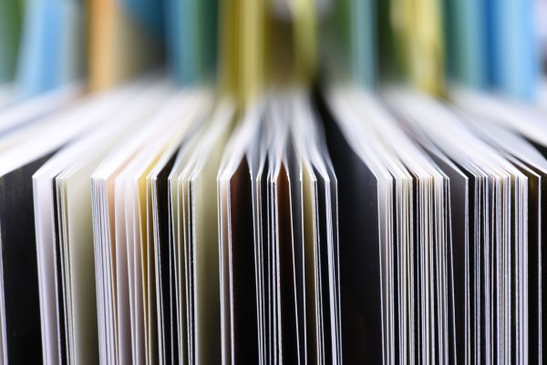 Nahaufnahme einer Reihe aneinandergereihter Bücher mit bunten Einbänden.