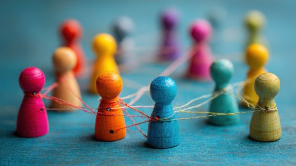 Bunt bemalte Holzfiguren sind durch Fäden netzwerkartig miteinander verbunden.