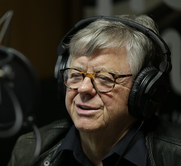 Fitzgerald Kusz: Ältere Person mit Brille und Kopfhörern spricht in ein Mikrofon in einem Tonstudio.