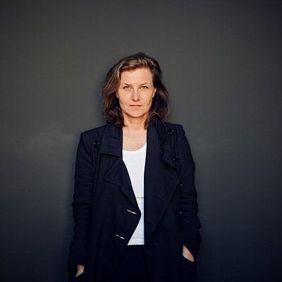 Portrait der Autorin Jacqueline Kornmüller. Sie trägt einen dunklen Mantel und sieht in die Kamera.
