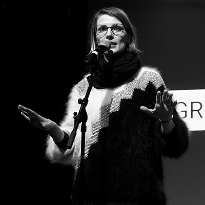 Pauline Füg auf der Bühne bei einem vergangenen Poetry-Slam. Bild in schwarz-weiß.