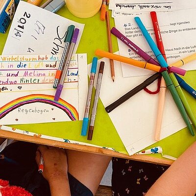 Papier und bunte Stifte auf einem Tisch.