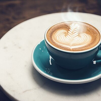 Hot coffee with Rosetta latte art pattern in the cup on a plate