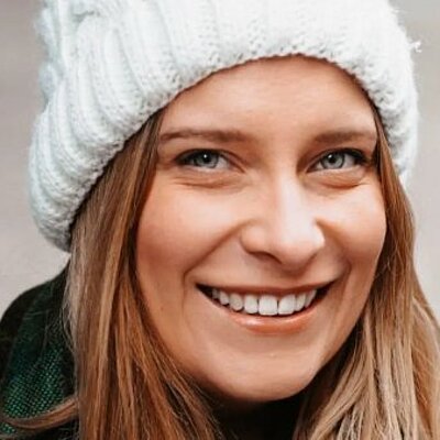 Ivy Leagh lächelt mit weißer Strickmütze